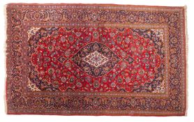 A Kashan carpet, the wine field with a central indigo and ivory cartouche pole medallion,