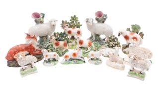Fourteen pearl ware and porcelain sheep figures, comprising taper vase groups with granular coats,