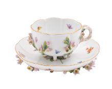 A Meissen porcelain cabinet cup and saucer, of lobed form each set on six rustic peg feet,