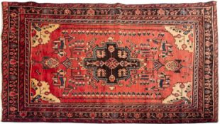 A Malayer rug, the brick red field with a geometric medallion,
