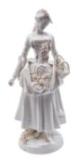A Marcolini Meissen porcelain figure of a lady flower seller standing with a basket and apron full