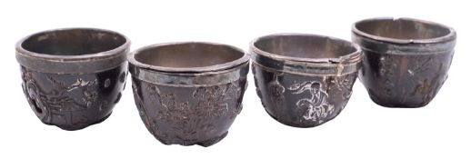 A set of four small Chinese carved coconut shell cups, Qing dynasty with silver rims and liners,