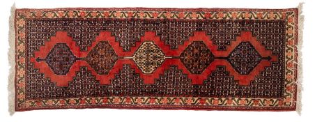 A Senneh runner, the brick red field with a row of five stepped hexagonal pointed medallions,