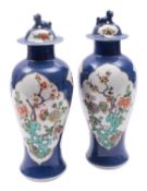 A matched pair of Chinese porcelain powder blue ground baluster vases and covers enamelled in the