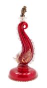 A Murano 'dolphin' lamp of red and clear gold flecked glass on a wrythen circular base,