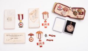 A collection of yellow metal and enamel British Red Cross medals and badges awarded to Ms EM