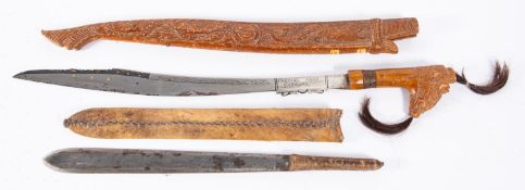 A Sudanese short sword in hide scabbard (blade stuck in scabbard) and a reproduction Dyak style