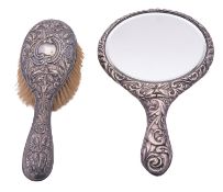 An early 20th century silver hand mirror & hairbrush, both with embossed foliate scroll decoration,