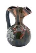 An Elton Pottery ewer with trefoil rim with floral slip ware decoration on a green ground,