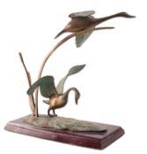 A patinated metal group of swans rising from bullrushes,