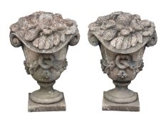 A pair of stone composition garden ornaments or pier finials modelled as urns, in Rococo taste,
