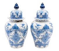 A pair of Dutch Delft lobed jars and domed covers each painted in blue with a broad band of