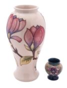 A John Moorcroft pottery baluster vase tube lined in the Magnolia pattern on an ivory ground,