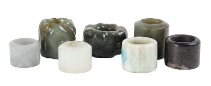 A group of seven jade archer's rings, 20th century two carved with flowers, in a circular ebony box,