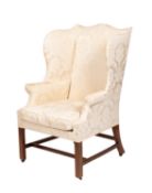 An upholstered wing armchair in George III style,