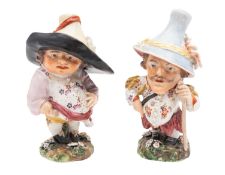 A pair of Derby Mansion House dwarfs, circa 1790-1800 wearing large hats and colourful costume,