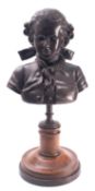 A patinated metal library bust of a boy in 18th century attire,