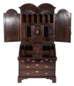 An early 18th century walnut double dome bureau cabinet, the upper part with a moulded cornice,