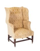 A stained beech wing frame armchair in the George III manner, fully upholstered in embossed fabric,