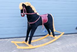 A vintage Rocking Horse made by Mamas and Papas, black with red saddle and bridle set,