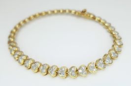 An 18K Yellow Gold Diamond Tennis Bracelet in Heart-Shaped Links. Over 100 round brilliant cut