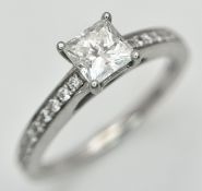 AN 18K WHITE GOLD, PRINCESS CUT DIAMOND SOLITAIRE RING, WITH DIAMOND SET SHOULDERS. 0.50CT CENTRE.