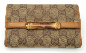 A Gucci Beige and Brown Monogram Canvas Wallet with a Bamboo Clasp Closure. Brown leather