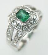 An 18K White Gold, Emerald and Diamond Cocktail Ring. 0.3ct centre emerald with a diamond surround