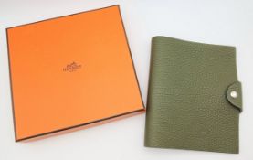 An Hermès Olive Green Togo Leather Ulysse Notepad Cover. Olive green leather exterior with silver-