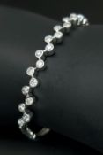 An 18K White Gold and Diamond Bangle/Bracelet. 22 round brilliant cut set diamonds in a flowing