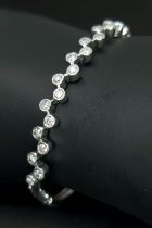 An 18K White Gold and Diamond Bangle/Bracelet. 22 round brilliant cut set diamonds in a flowing