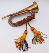 A vintage brass and copper bugle, with multi coloured ceremonial ties, mouth piece included.