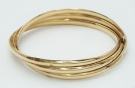 A 9K Yellow Gold Twist Bangle. 14mm widest part. Clip open design. Two small dings. 55mm inner