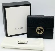 A Gucci Dollar Calfskin Interlocking G French Wallet. Black grained leather exterior with a gold-