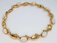 A Spellbinding 14K Yellow Gold and Opal Tennis Bracelet. Alternating oval shapes of rich gold and