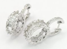 A Pair of 18K White Gold and Diamond Hoop Dress Earrings. 1.21ctw of baguette, oval and round