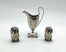 A cream jug, together with a pair of pepperettes,