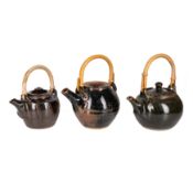 Studio pottery by various makers Three tenmoku glazed teapots with cane handle