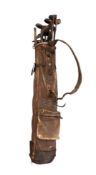 A vintage golf bag containing a quantity of golf clubs to include hickory shafted examples.