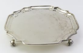 A square silver salver upon four thick scrolled