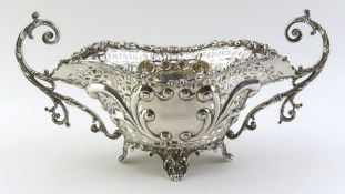 A wide and decorative silver basket, upon four scrolled