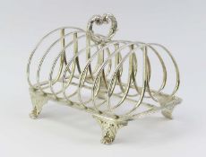 A silver toast rack with seven curved ranks with a decorative floral handle