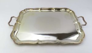 A large silver serving tray with a scalloped edge and plain base