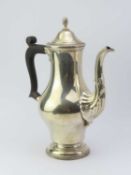A silver coffee pot on circular base