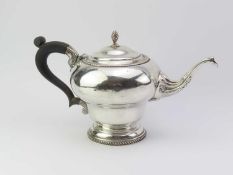 A silver teapot on circular base