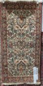 Persian-style cream ground rug with floral pattern field, single herati border, 140cm x 70cm