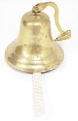 Reproduction brass ship's bell on a swinging wall bracket, the clapper with rope handle, bell 15cm