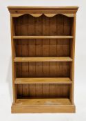 Pine bookcase with wavy shaped frieze, three fixed shelves, on a plinth base, 123cm high x 76cm wide