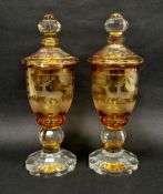 A pair of 19th century Bohemian cut glass pedestal vases and covers, amber glass engraved with stags