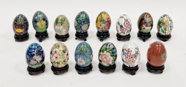 Fourteen Chinese cloisonne eggs on wooden stands, 20th century, variously decorated with birds,